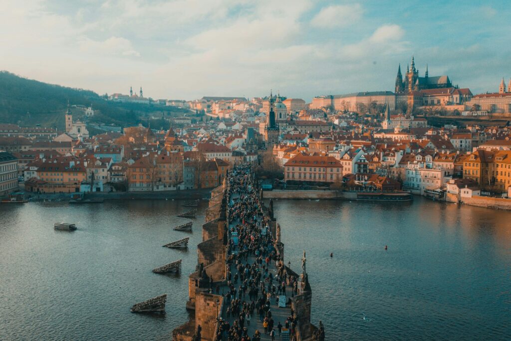 people walking on bridge over river with town in the background with church