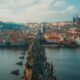 people walking on bridge over river with town in the background with church